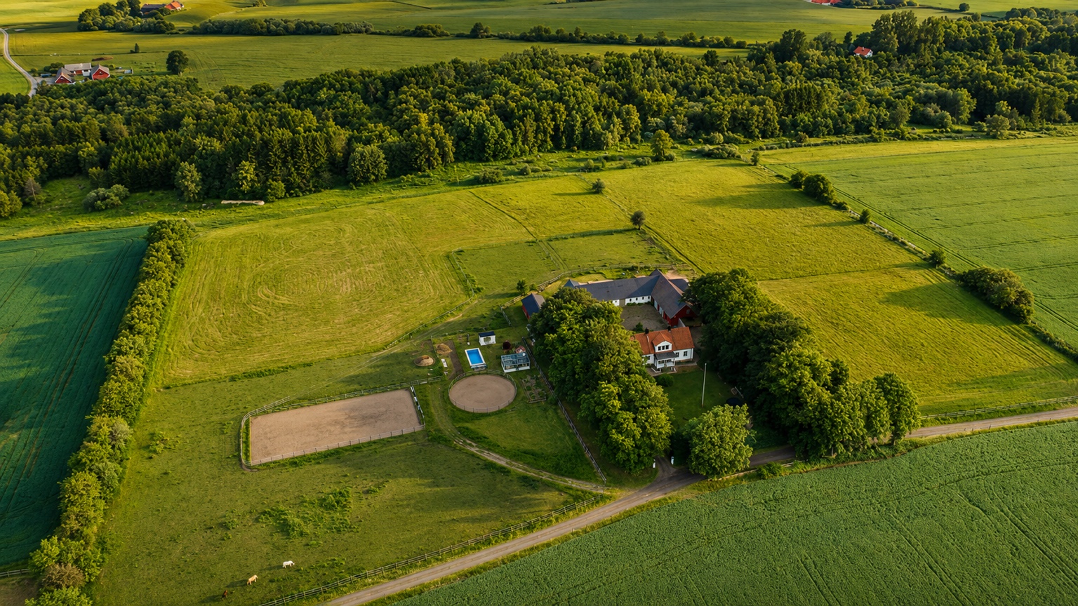 Flygvy över Åkeslund, omgiven av hagar, åkrar och skog